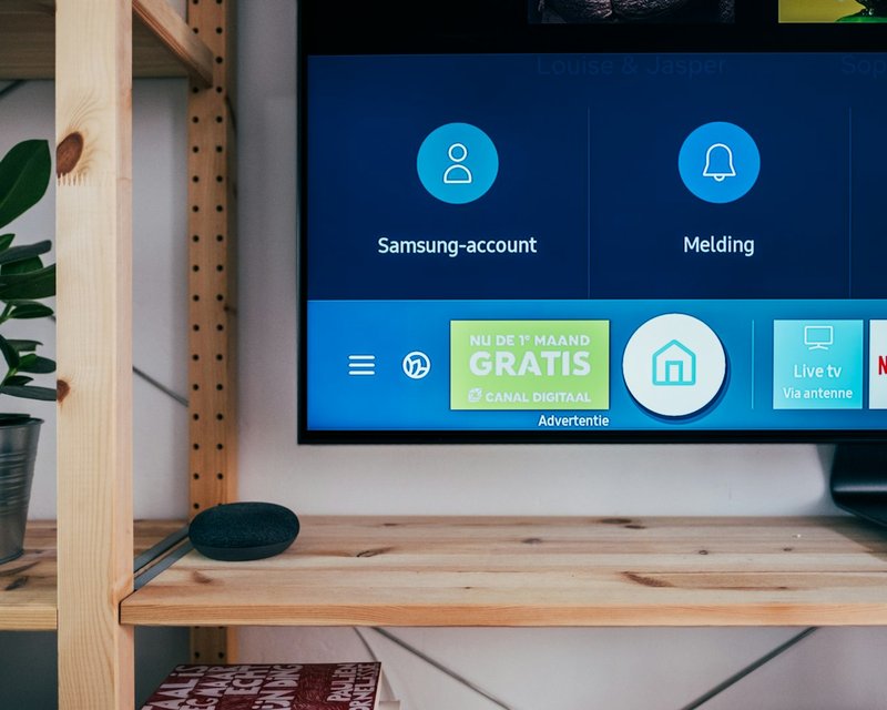Samsung smart TV and smart speaker sitting on a wooden shelf